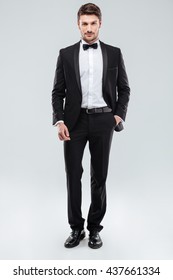 Confident attractive young man in tuxedo standing with hand in pocket