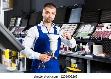 Confident Auto Mechanic Of Car Painting Workshop Pouring Paints In Paint-spray Gun