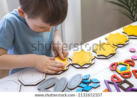 Confident baby boy assembling geometric pattern multicolored shape connecting details childish early development. Cute male kid playing wooden constructor pieces learning intelligence logic tasks