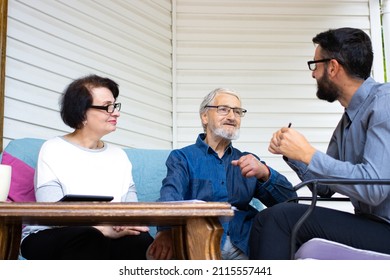 Confident Bank Manager Consulting Old Senior Couple Clients At Meeting Sitting At Home Terrace. Pension Planning, Medical Health Insurance, Buying Property, Closing Deal With Male Bank Specialist