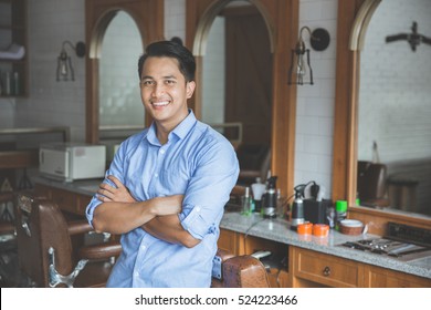 Confident barber expert. Young man looking at camera and smiling standing at barbershop