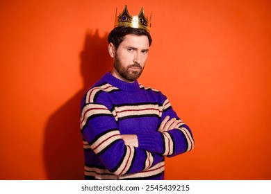 Confident bearded man wearing a colorful striped sweater and golden crown against bright orange background. - Powered by Shutterstock