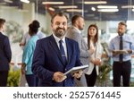 Confident bearded mature serious business man, successful company leader, founder, professional speaker posing with documents, happy looking at camera, businessman corporate portrait at meeting