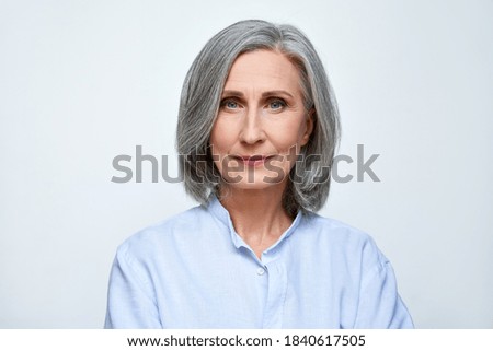 Confident beautiful mature business woman standing isolated on white background. Older senior businesswoman, 60s grey haired lady professional looking at camera, close up face headshot portrait.