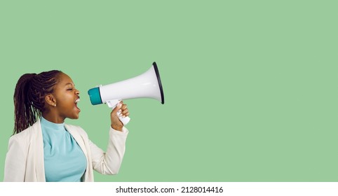 Confident beautiful young black woman holding and yelling through megaphone. Loud activist girl makes important news announcement standing on blank green colour text copyspace studio banner background