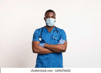 Confident black doctor in face mask and gloves over white studio background, copy space