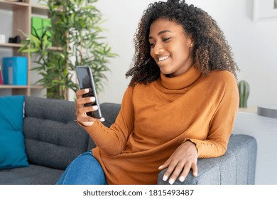 Confident Black Woman Scrolling On Smartphone At Home