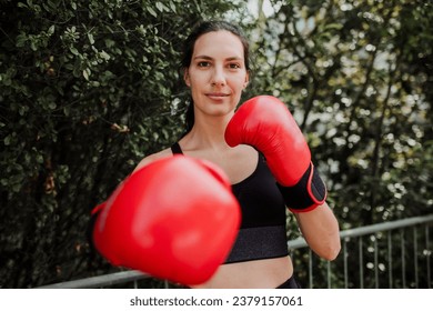 Confident boxer woman in red boxing gloves standing outdoors. Woman boxing for relaxation and bolsting mental health. Boxing empowers women. - Powered by Shutterstock