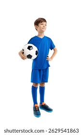 Confident boy in blue sport outfit posing with classic soccer ball over white background.