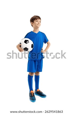 Confident boy in blue sport outfit posing with classic soccer ball over white background.