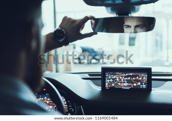 Confident Buisiness Man\
Look At Back Car Mirrow. Portrait of Handsome Caucasian Bearded\
Stylish Person Driving Car in Town Using Road GPS Navigator. Auto\
Driving Concept