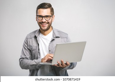 Confident business expert. Confident young handsome man in shirt holding laptop, looking at camera and smiling while standing against white background - Shutterstock ID 1070871419
