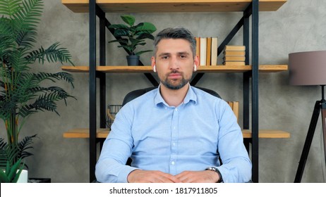 Confident Business Man In Home Office Wearing Wireless Earphones Looks Camera Listens Conducts Remote Distant Online Interview Potential Employee To Company By Video Chat Conference, Web Cam Concept