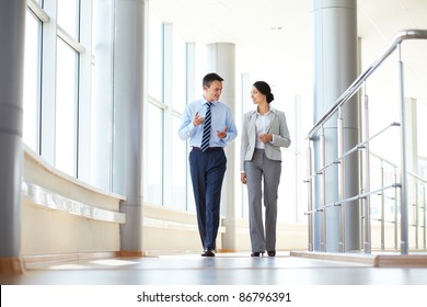 Confident business partners walking down in office building and talking