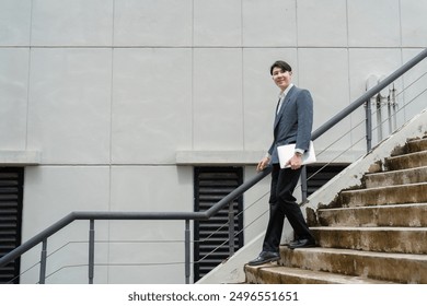 Confident Business Professional Walking Downstairs with Documents in Hand Outside Modern Office Building - Powered by Shutterstock