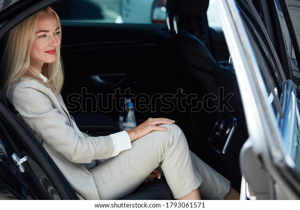 confident business woman\
inside of car, elegant blonde lady feel safety and comfort, in\
luxurious taxi