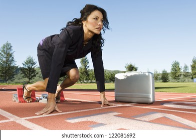 Confident business woman at start position of a racing track with briefcase against sky - Powered by Shutterstock