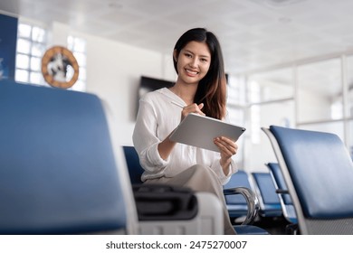 Confident Business Woman Using Tablet at Airport Lounge, Professional Traveler, Modern Business Travel, Corporate Journey, Businesswoman in Airport, Efficient Travel, Business Technology - Powered by Shutterstock