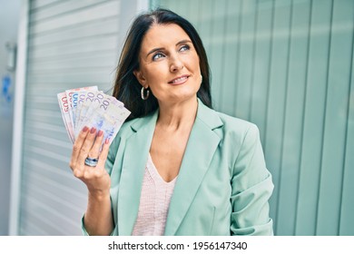 Confident business woman wearing elegant suit standing at the street holding swedish krona banknotes