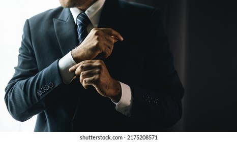 Confident businessman buttoning or adjust classic blue suit near window in hotel room at the morning. Handsome man wearing a nice suit on wedding day. - Powered by Shutterstock