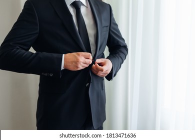 Confident businessman. Cropped shot of a businessman in a stylish black suit straightens his jacket. - Powered by Shutterstock