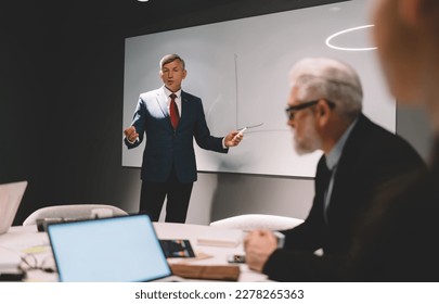 Confident businessman in elegant suit making presentation with colleagues while having meeting at office and discussing business strategy during workday - Shutterstock ID 2278265363