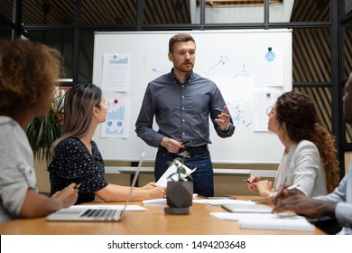 Confident Businessman Executive Mentor Ceo Leader Talk To Employees Group During Corporate Briefing In Boardroom, Serious Male Boss Explain Work Plan To Multiethnic Workers At Office Meeting Table