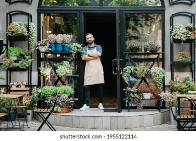 Confident businessman, flower shop owner and ad of modern studio in rustic style. Smiling millennial confident male hipster in apron with crossed arms at store with plants in pots and vases outdoor - Powered by Shutterstock