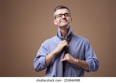 Confident businessman getting dressed and adjusting his tie knot - Powered by Shutterstock