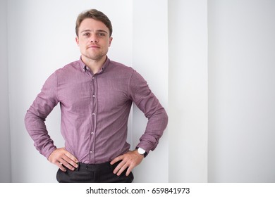 Confident Businessman With Hands On Hips In Office