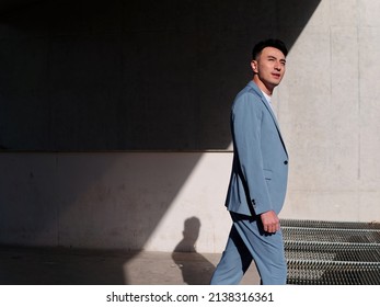 Confident Businessman, Portrait Of Handsome Chinese Young Man In Light Blue Suit Smiling And Walking Into Sunlight, Side View.