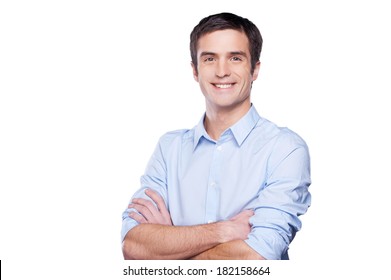 Confident businessman. Portrait of handsome young man in blue shirt looking at camera and keeping arms crossed while standing isolated on white