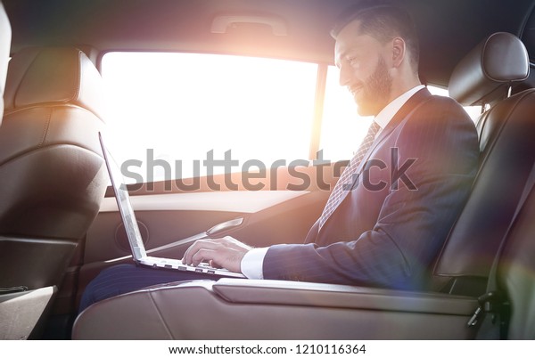 confident businessman sitting on the backseat of a\
prestigious car