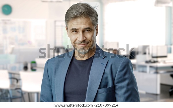 Confident businessman smiling in modern business\
office. Portrait of mature age, middle age, mid adult man in 50s,\
happy confident smile. Copy\
space.