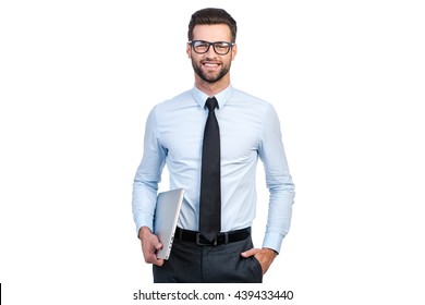 Confident Businessman. Confident Young Handsome Man In Shirt And Tie Carrying Laptop And Looking At Camera With Smile While Standing Against White Background