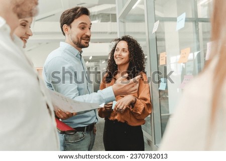 Confident businesspeople using sticky notes, agile methodology for productivity working in modern office. Successful scrum master planning strategy, startup, talking, brainstorming. Teamwork, scrum