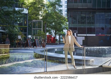 Confident Businesswoman In Beige Suit, Standing In Power Pose In City Center.