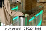 A confident businesswoman effortlessly passes through a modern turnstile using her personal access card in a sleek office lobby. Ideal for concepts of advanced security, workplace technology.