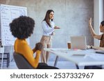 A confident businesswoman leads a team meeting in a modern office. Colleagues are engaged, collaborating, and participating actively in the workplace discussion for effective teamwork and productivity