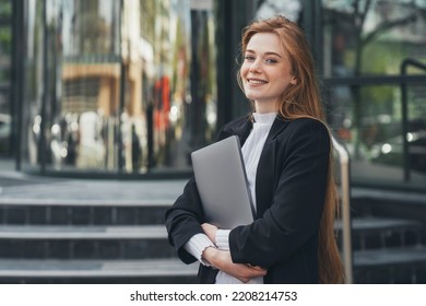 Confident businesswoman model holding laptop looking at camera smiling toothy standing outside outdoor near company. Caucasian female business person on city - Powered by Shutterstock