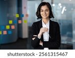 Confident businesswoman in modern office holding glasses, portraying leadership, professionalism, success. Ideal for business, corporate, professional, and leadership themes.