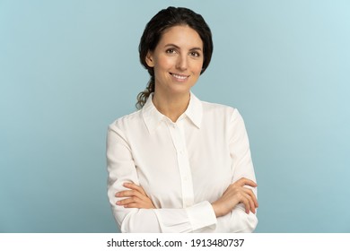 Confident businesswoman or office employee, smiling, looking at camera posing isolated on blue background. Studio portrait of successful friendly female lawyer in blouse, crossed arms.