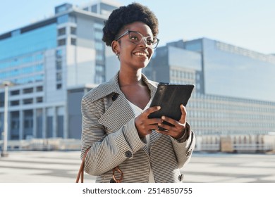 Confident Businesswoman Smiling Outdoors with Tablet in Urban Setting - Powered by Shutterstock