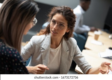 Confident businesswoman wearing glasses discussing project with colleague close up, diverse employees working together, executive consulting Asian woman client, mentor teaching trainee in office - Shutterstock ID 1673172736