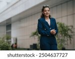 Confident businesswoman wearing a striped suit walking in a modern urban business district, representing leadership and professionalism.