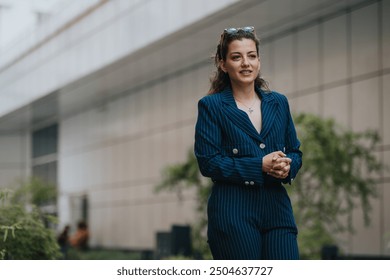 Confident businesswoman wearing a striped suit walking in a modern urban business district, representing leadership and professionalism. - Powered by Shutterstock