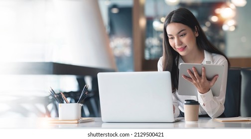 Confident businesswoman working on digital tablet and laptop at her workplace at modern office.