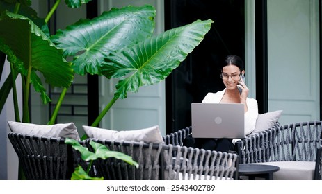 Confident businesswoman working on laptop and talking on phone in office. The concept of business negotiations, consultation and effective work in a modern business environment. - Powered by Shutterstock