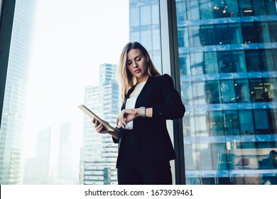 Confident caucasian female manager checking notification on wearable smartwatch with touchscreen and apps standing in office, millennial business woman in elegant formal wear using modern gadgets - Powered by Shutterstock