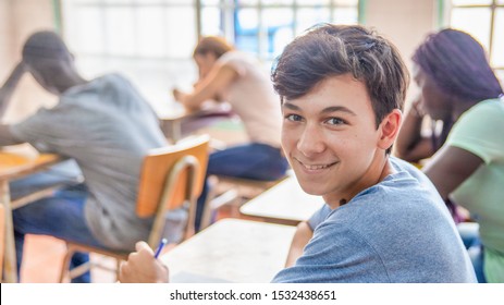Confident caucasian teenager boy in the classroom doing school test.